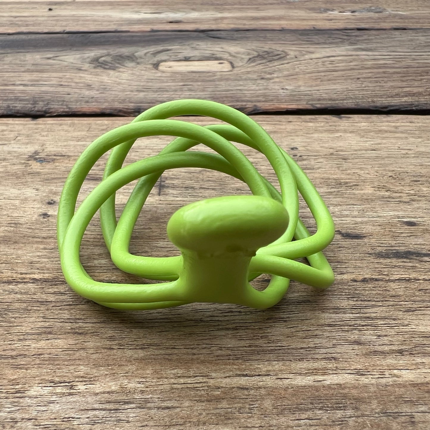 A polished green Velv'Or JNamo intimate massager featuring a unique, flexible looped ergonomic design with a smooth perineum part