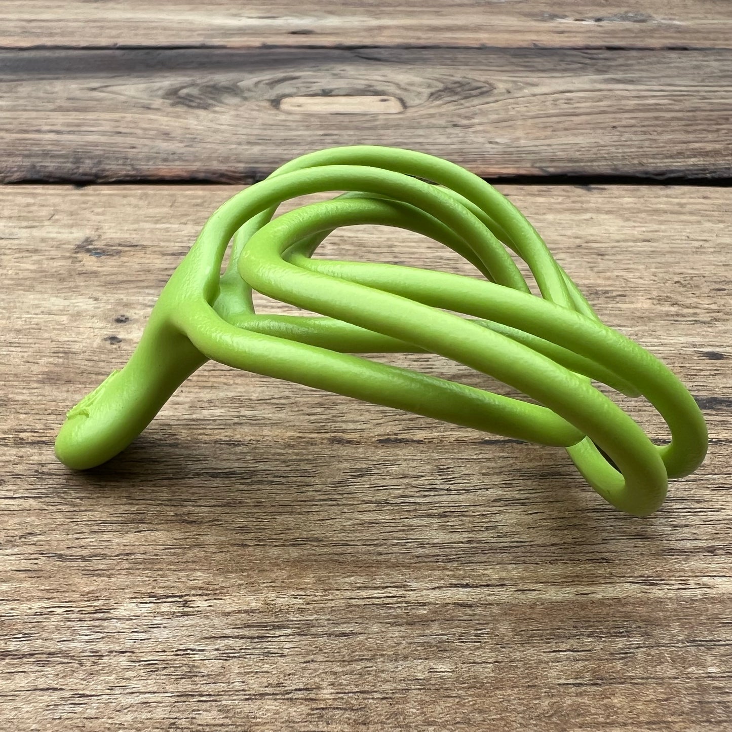 A polished green Velv'Or JNamo intimate massager featuring a unique, flexible looped ergonomic design with a smooth perineum part