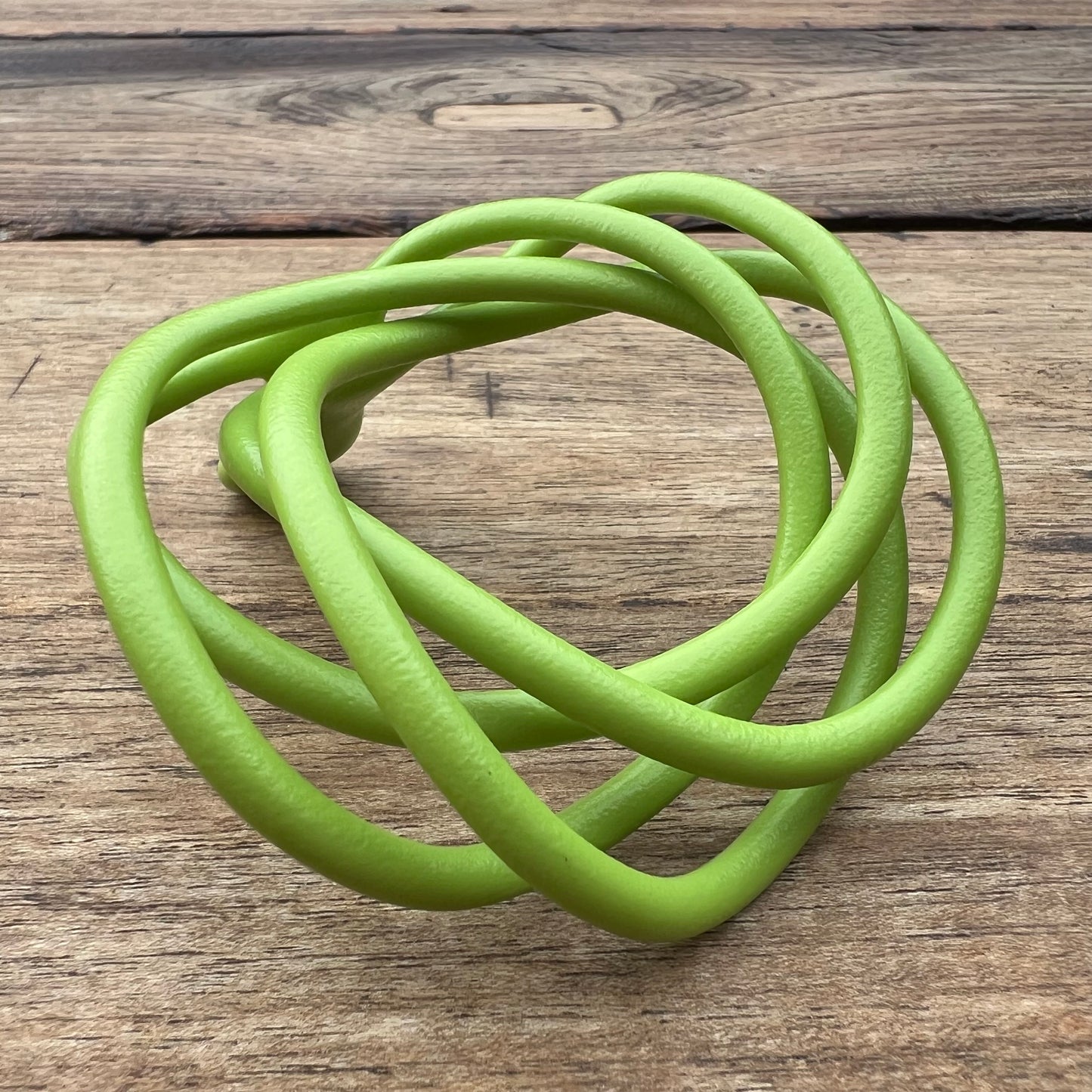 A polished green Velv'Or JNamo intimate massager featuring a unique, flexible looped ergonomic design with a smooth perineum part