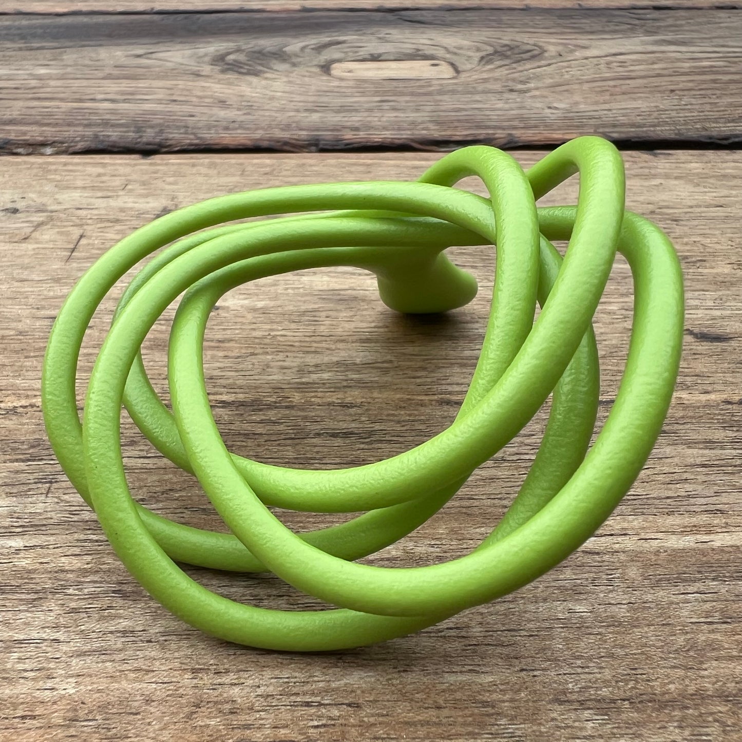 A polished green Velv'Or JNamo intimate massager featuring a unique, flexible looped ergonomic design with a smooth perineum part