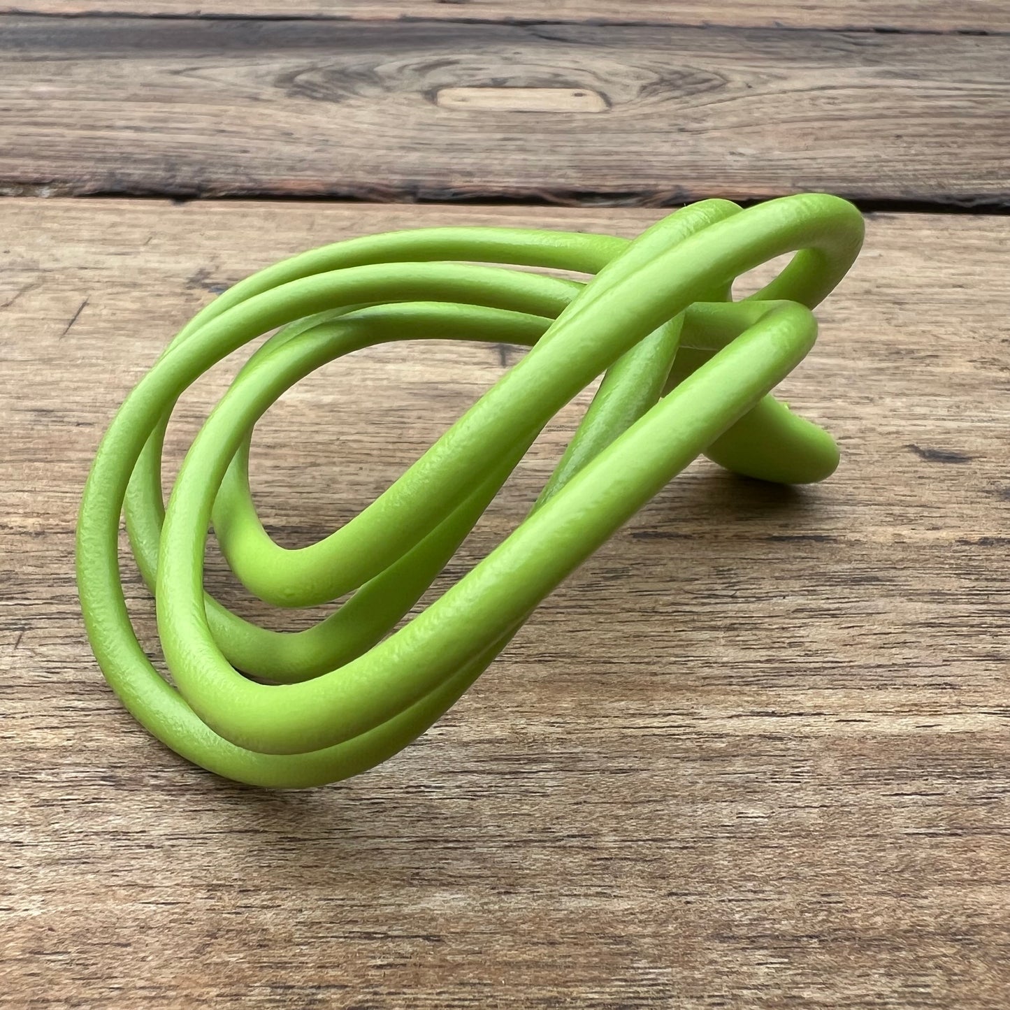 A polished green Velv'Or JNamo intimate massager featuring a unique, flexible looped ergonomic design with a smooth perineum part