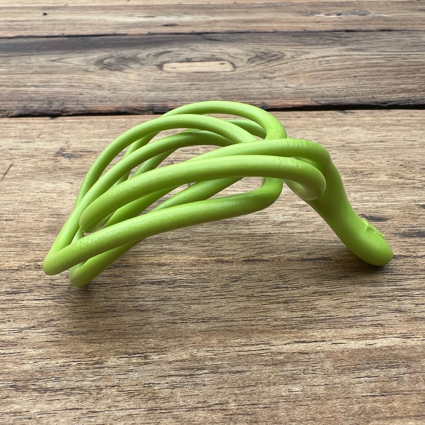 A polished green Velv'Or JNamo intimate massager featuring a unique, flexible looped ergonomic design with a smooth perineum part