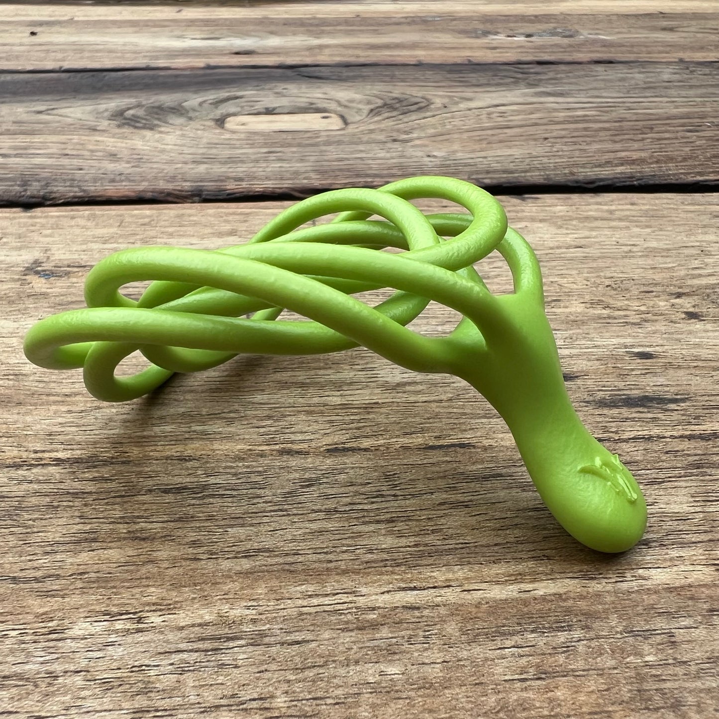 A polished green Velv'Or JNamo intimate massager featuring a unique, flexible looped ergonomic design with a smooth perineum part