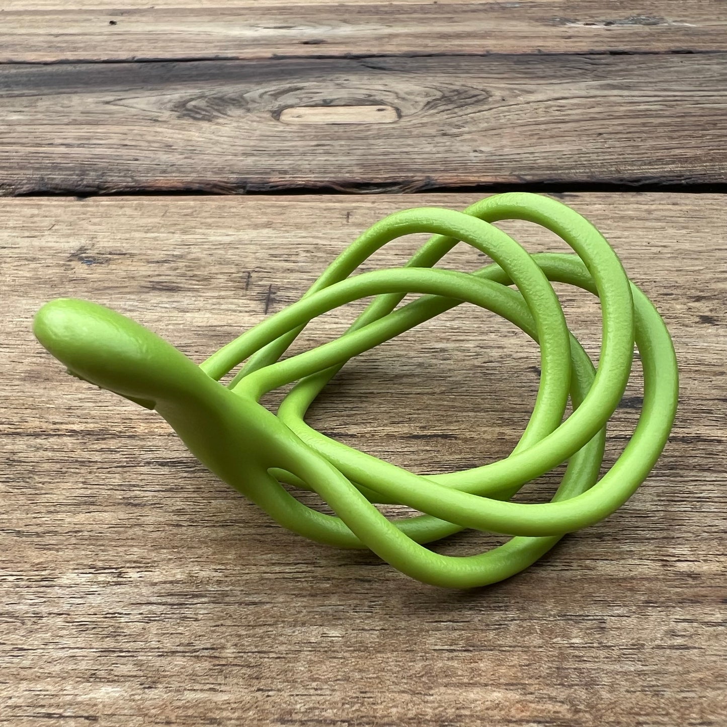 A polished green Velv'Or JNamo intimate massager featuring a unique, flexible looped ergonomic design with a smooth perineum part
