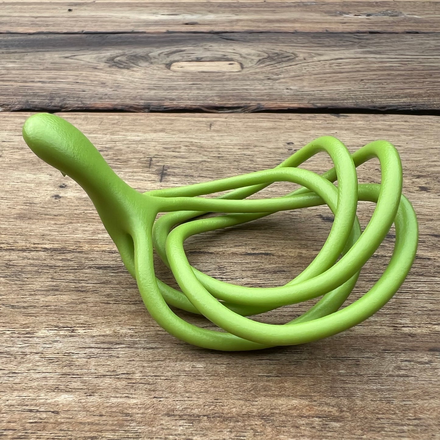 A polished green Velv'Or JNamo intimate massager featuring a unique, flexible looped ergonomic design with a smooth perineum part