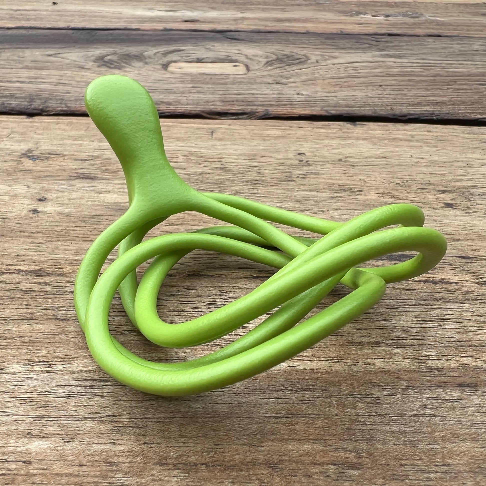 A polished green Velv'Or JNamo intimate massager featuring a unique, flexible looped ergonomic design with a smooth perineum part