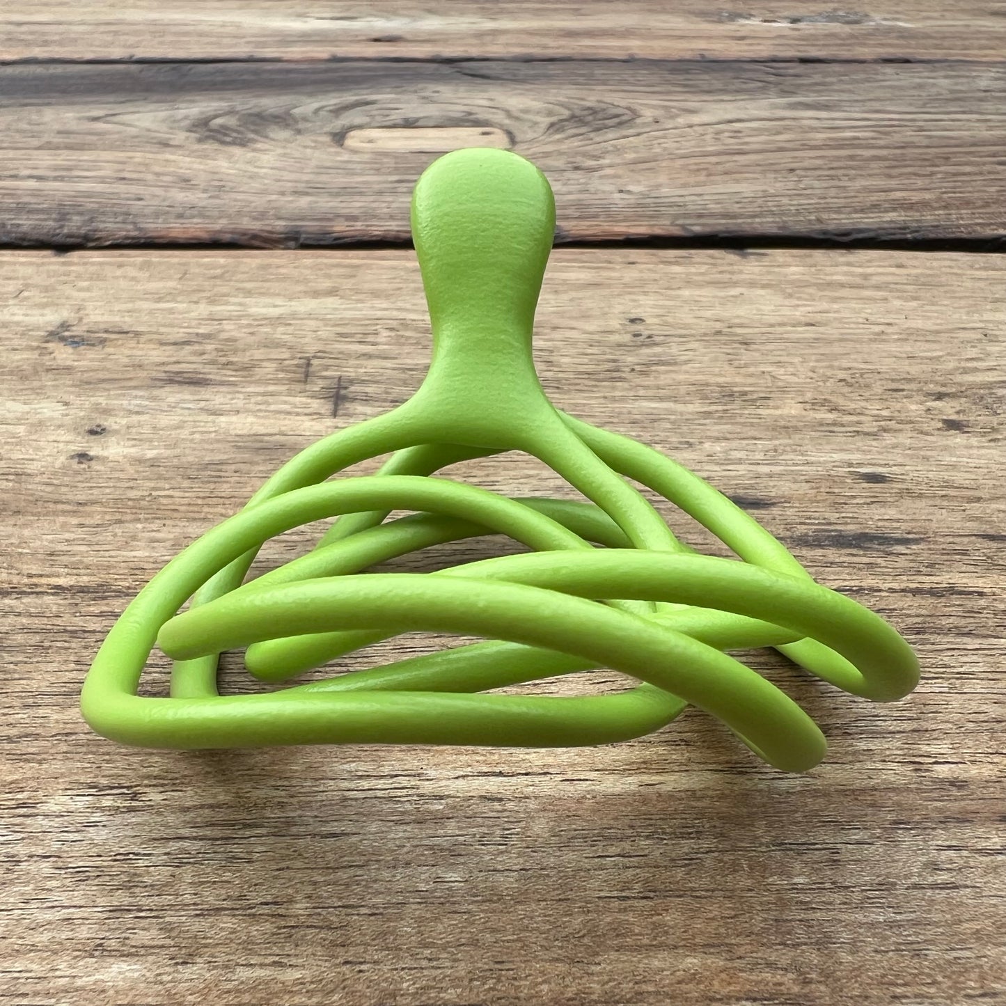 A polished green Velv'Or JNamo intimate massager featuring a unique, flexible looped ergonomic design with a smooth perineum part