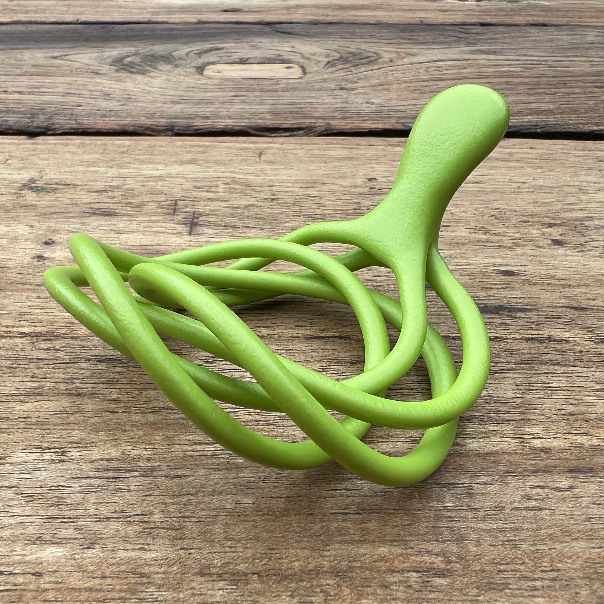 A polished green Velv'Or JNamo intimate massager featuring a unique, flexible looped ergonomic design with a smooth perineum part